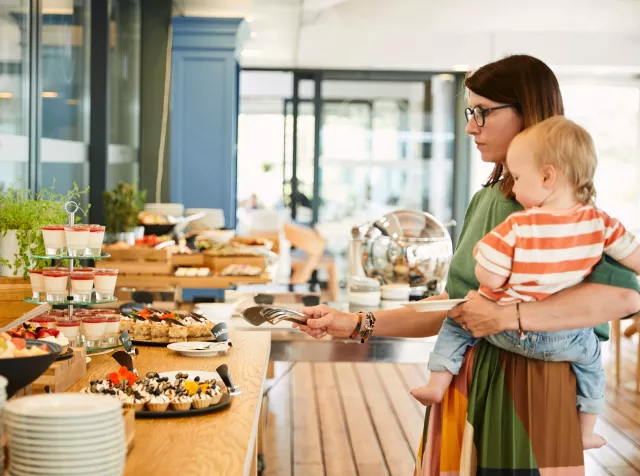 Žena s dítětem v náručí u bufetového stolu