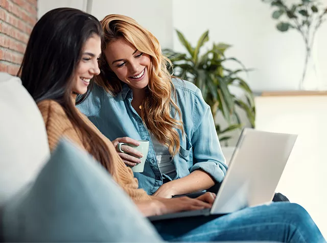 dvě usmívající se ženy s notebookem