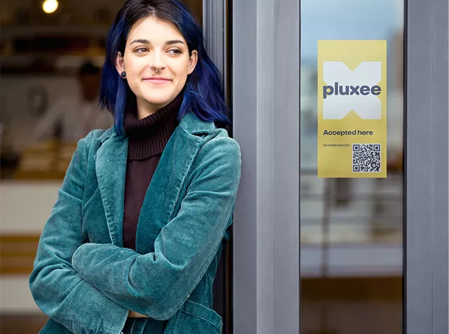 žena ve dveřích se žlutou nálepkou o akceptaci karet Flexi