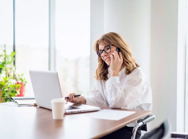 Telefonující žena v brýlích u počítače