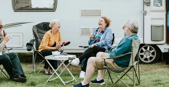 skupina lidí sedící před karavanem