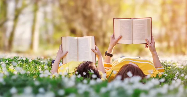 dva lidé s knihou v ruce na louce