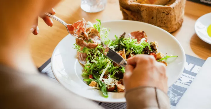 Žena si v restauraci dává k obědu lehký letní salát