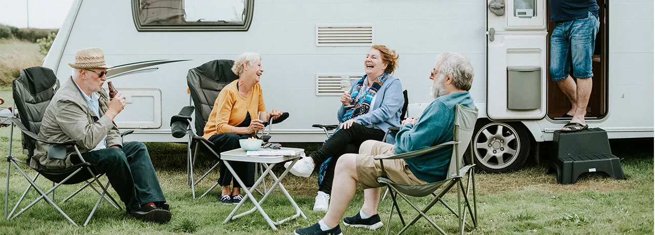 skupina lidí sedící před karavanem