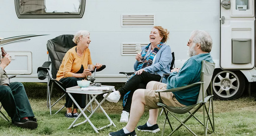 skupina lidí sedící před karavanem