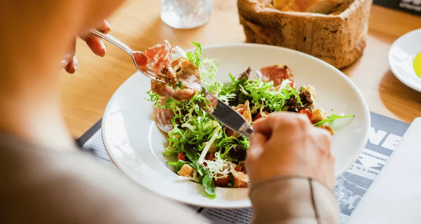 Žena si v restauraci dává k obědu lehký letní salát
