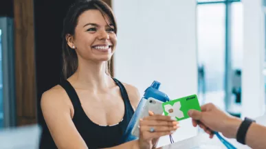 Žena drží Pluxee kartu u recepce fitness centra