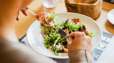 Žena si v restauraci dává k obědu lehký letní salát